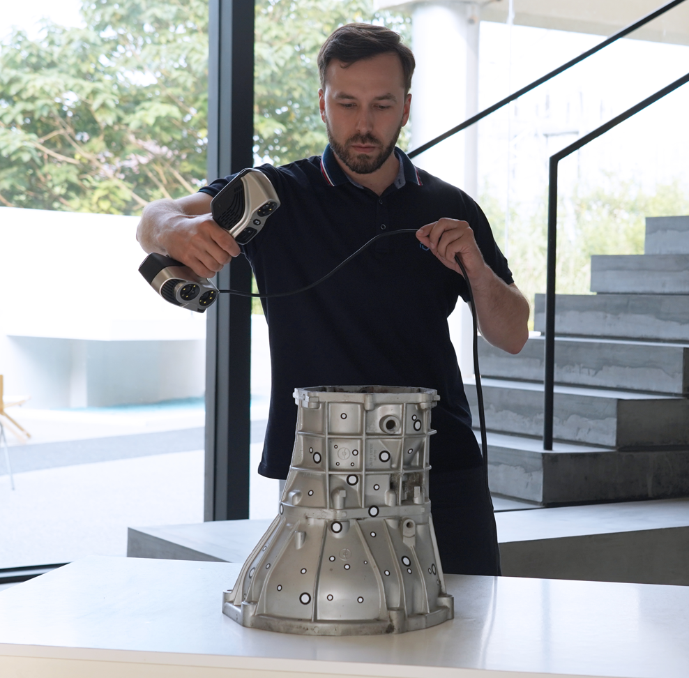 Technician scanning a cast aluminium part with a 3D scanner.
